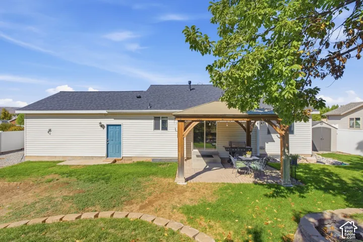 Spacious backyard featuring a covered patio, sliding glass door access, dedicated storage shed, and a circular stone fire pit