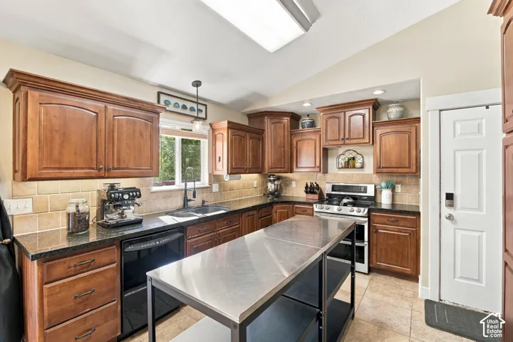 Kitchen featuring wood cabinetry, dark countertops, tiled backsplash, stainless steel appliances, and a central island