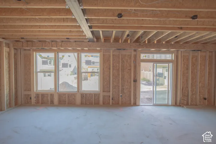 Framed interior space with exposed ceiling joists, three multi-pane windows, and a sliding glass door