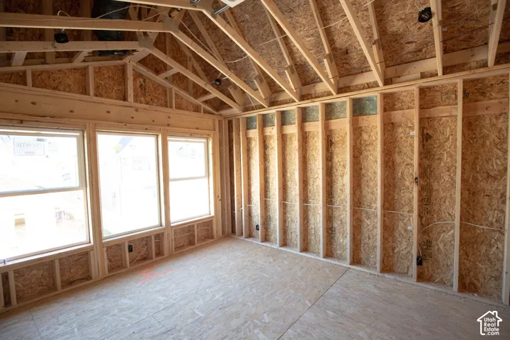 New construction framing with exposed wood studs, three large windows, and an angled roofline
