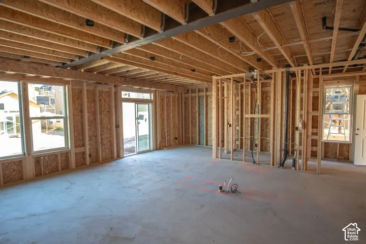 Open-concept space featuring exposed ceiling joists, multiple windows, and a sliding glass door