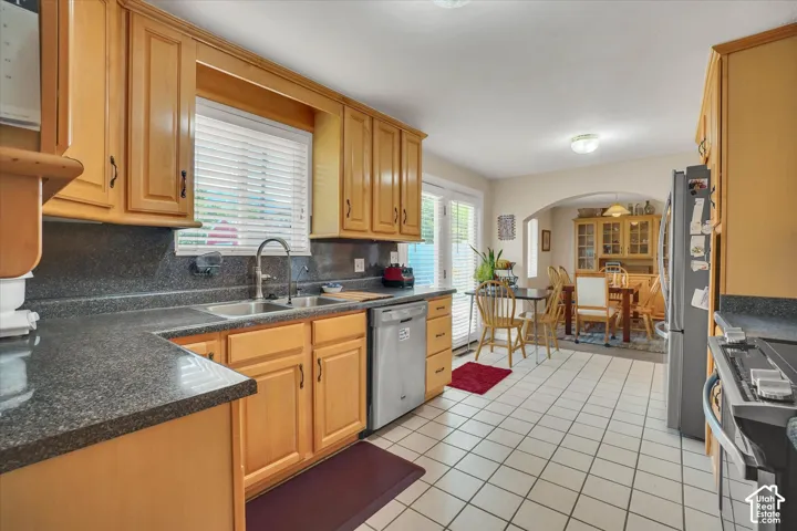 Maple cabinetry, dark countertops, tile flooring, stainless steel dishwasher, and French patio doors