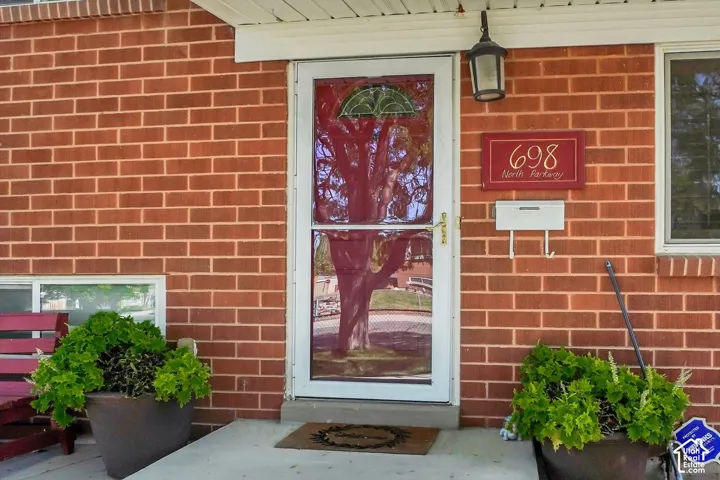 Brick exterior with a white storm door, featuring a decorative glass insert