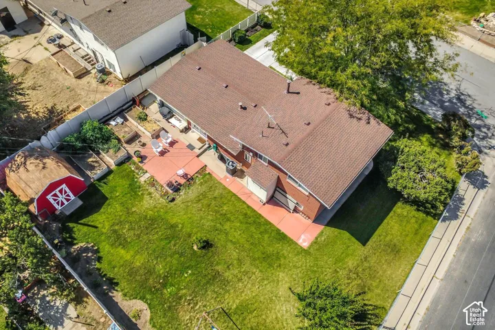 Expansive backyard with a manicured lawn, a red-painted storage shed, and a paved patio area