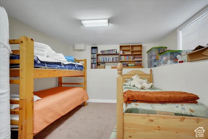 Neutral tone wall paint, recessed window with horizontal blinds, carpet flooring, and built-in shelving