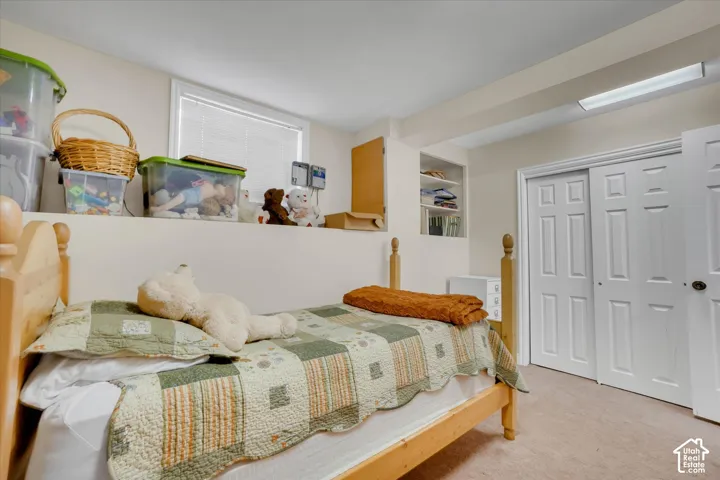 Built-in shelving, recessed window, bi-fold closet doors, wall-mounted light fixture, and carpeted flooring