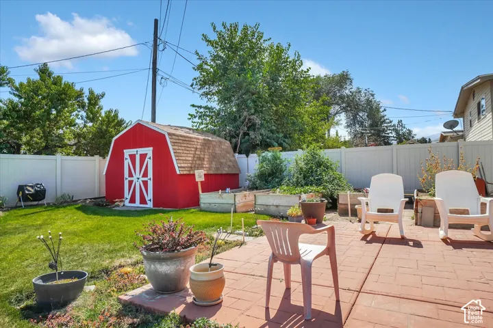 Expansive backyard featuring a red barn-style shed, private fencing, and a paver patio area