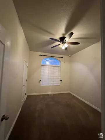 Vaulted ceiling with an attached ceiling fan, arched window with horizontal blinds, and carpeting