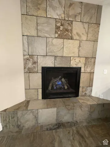 Corner fireplace with a stone tile surround and hearth, featuring a gas log insert