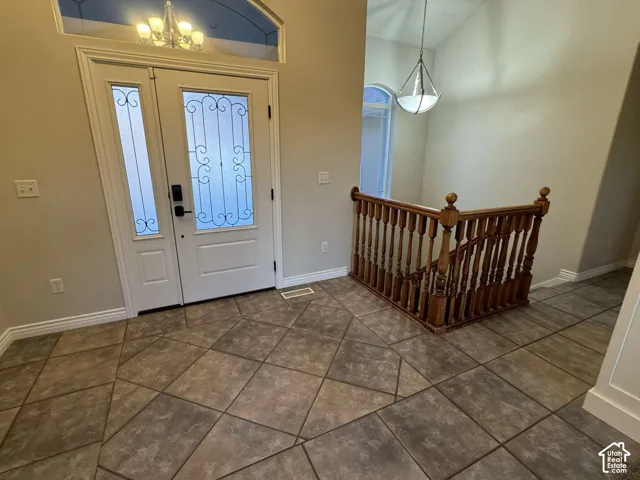 Entryway featuring patterned tile flooring, a decorative glass entry door with transom window, and a wood baluster staircase