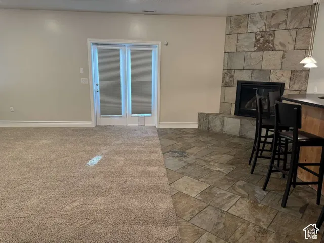 Stone-clad fireplace with a dark insert, double paneled glass doors with integrated blinds, and durable stone tile flooring