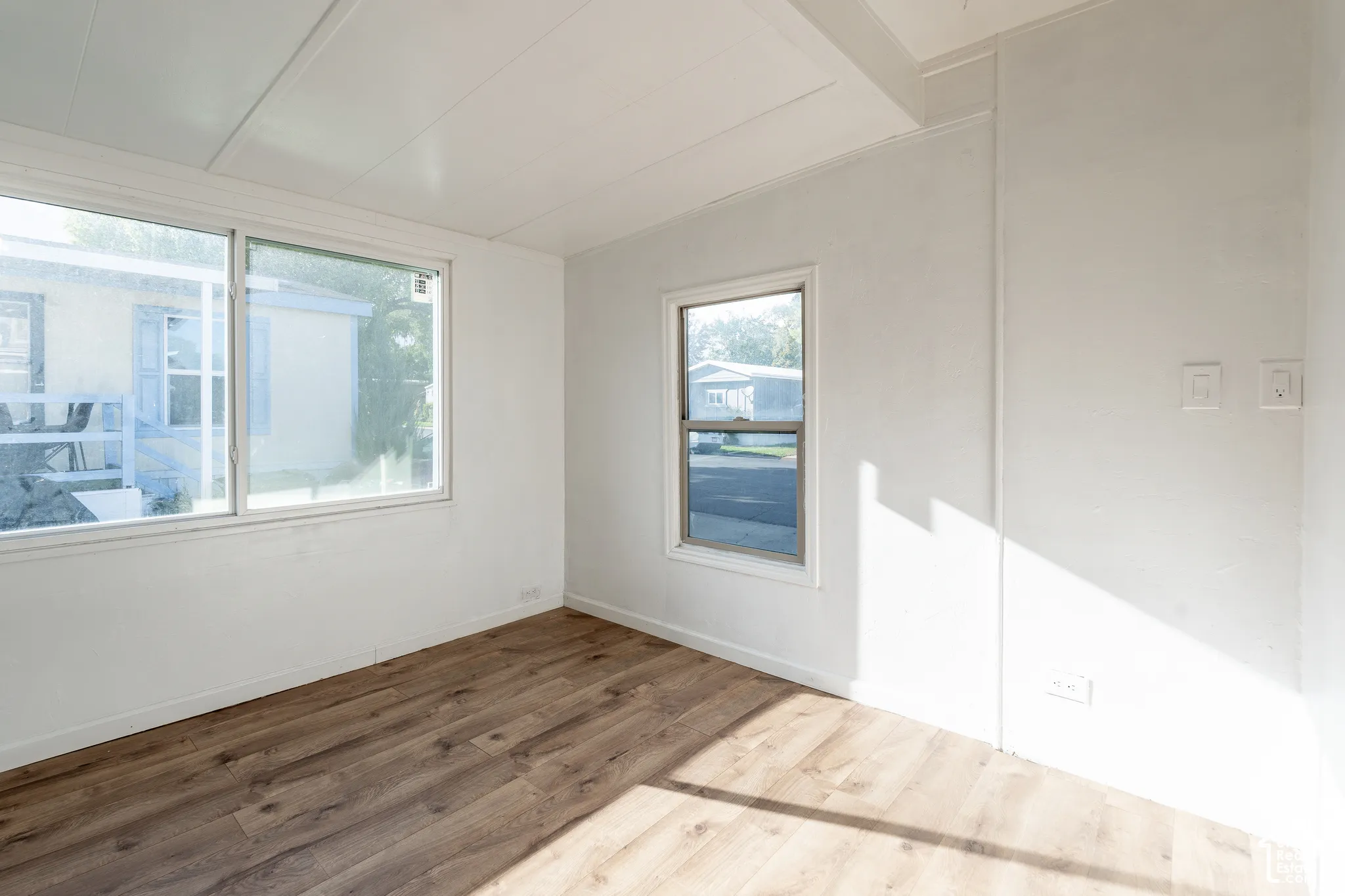 Wood-finish flooring, white walls, and multiple windows