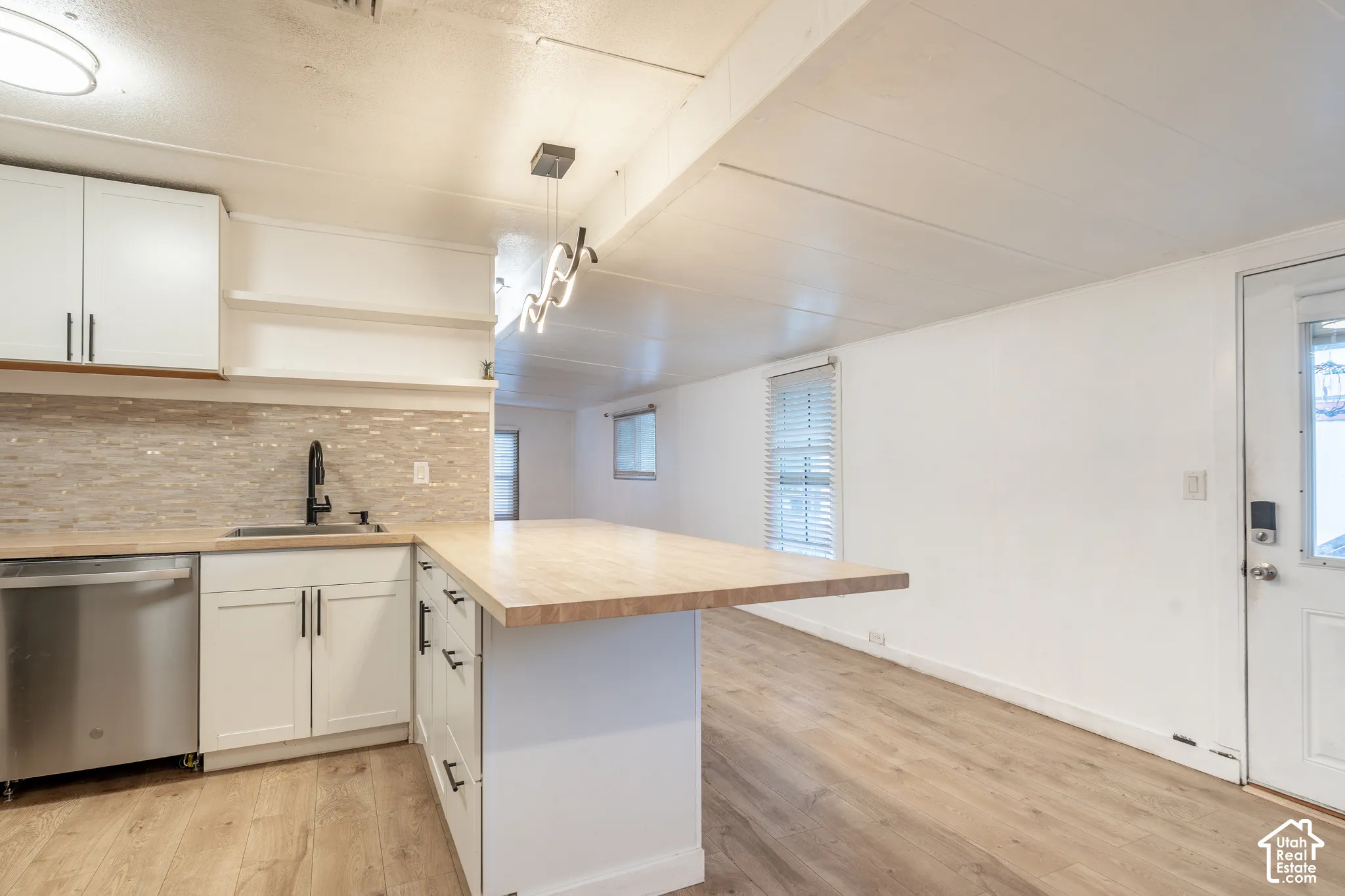 Kitchen featuring white cabinetry, light wood-finish countertops, and a tiled backsplash