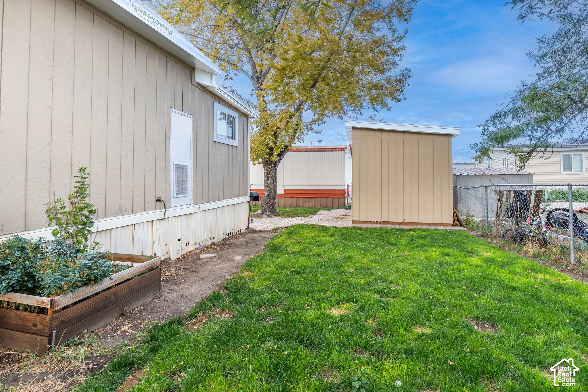 Manicured lawn with a detached storage shed, a wood-framed planter box, and a gravel path