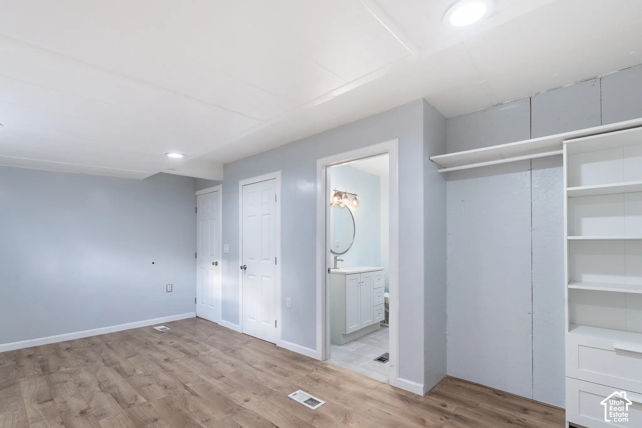 Wood-finish flooring, built-in shelving, recessed ceiling lighting, and a neutral wall color