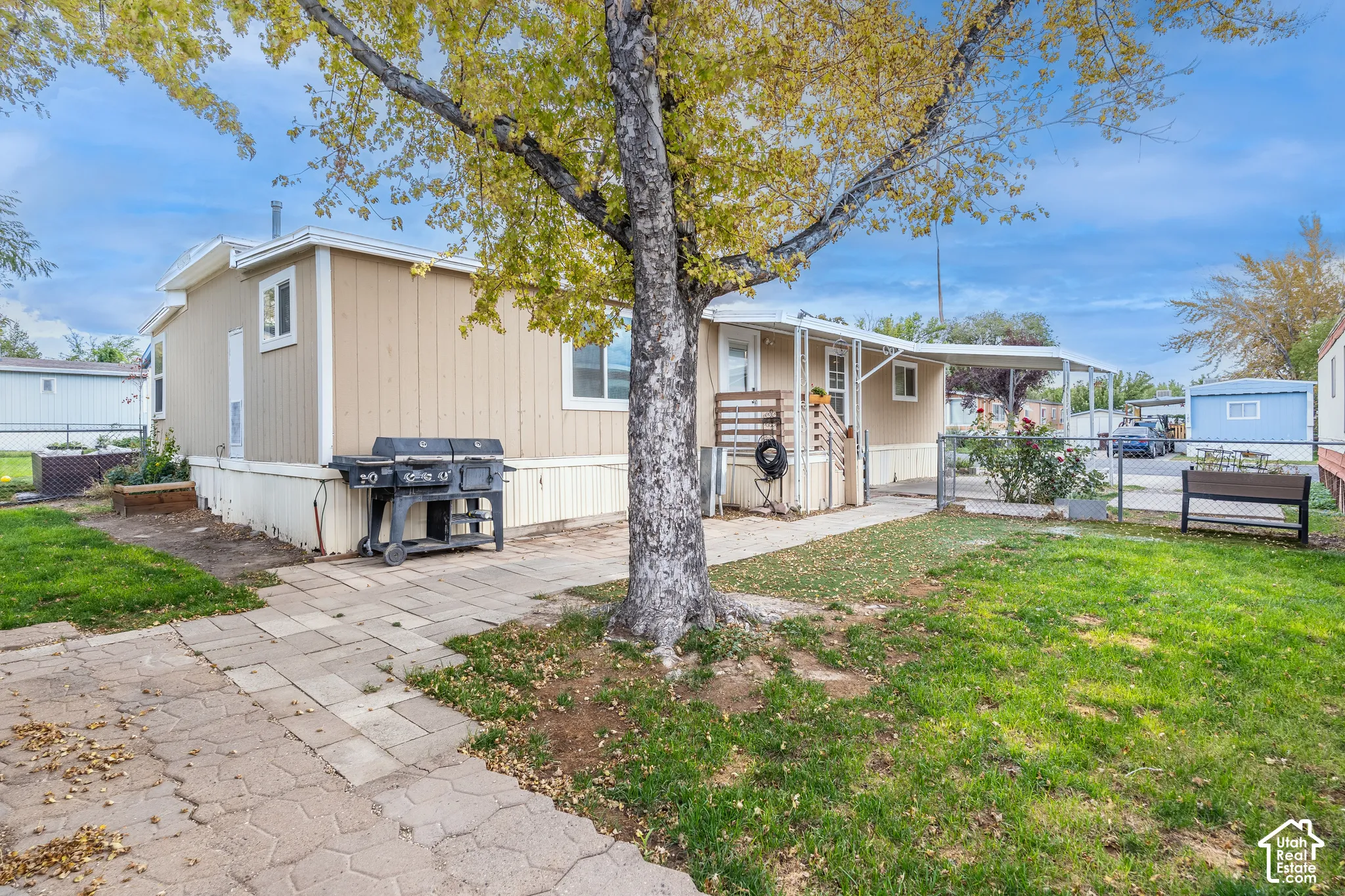 Exterior featuring neutral-toned siding, white trim, a covered entry, and a paved patio area