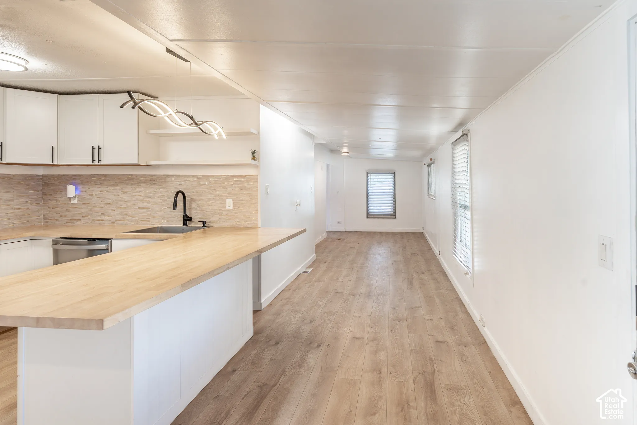 Open-concept living space featuring wood-finish flooring, white walls, and multiple windows