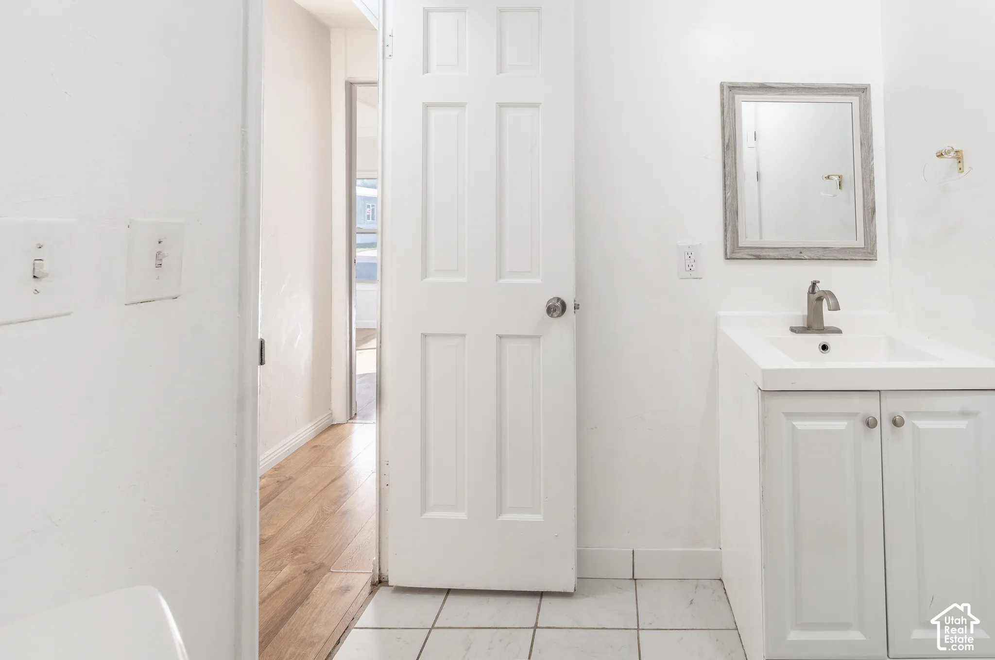 White vanity with paneled doors, integrated sink, and brushed nickel faucet