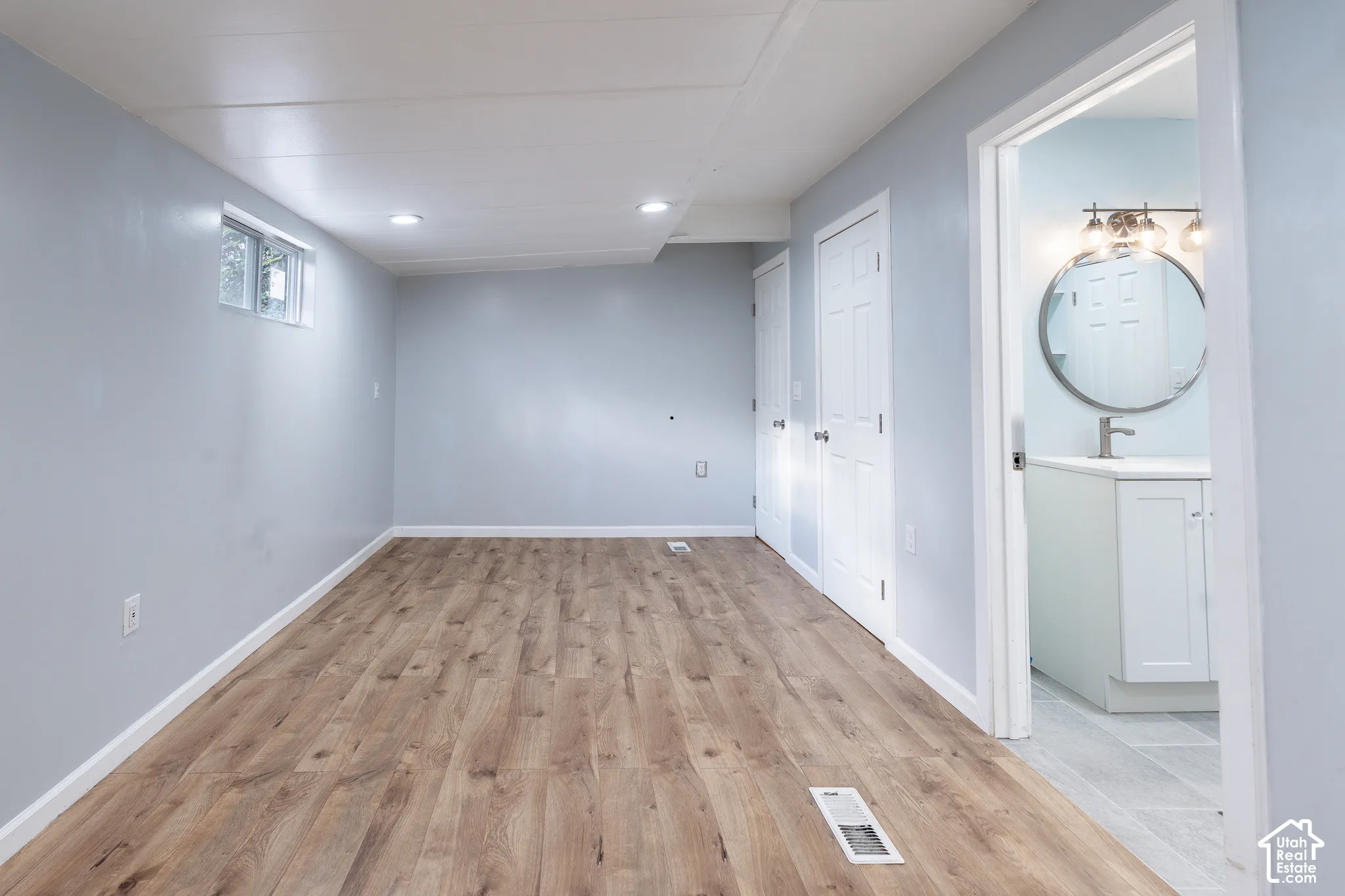 Spacious room featuring wood-finish flooring, recessed lighting, and light blue walls
