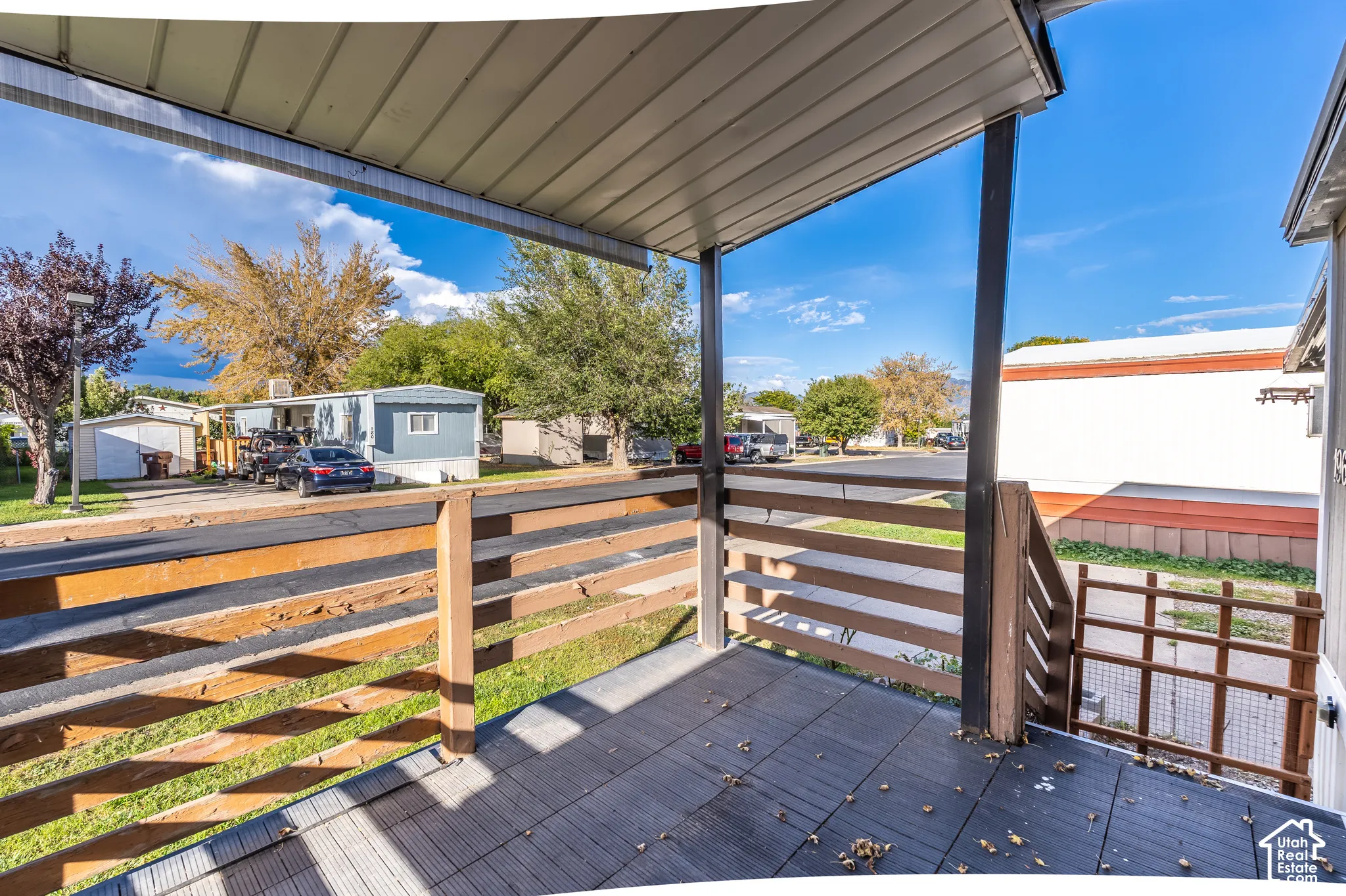 Covered outdoor deck with composite decking, slatted wood railing, and integrated steps