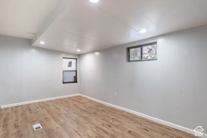 Recessed lighting, light wood-finish flooring, two windows, and light gray wall paint