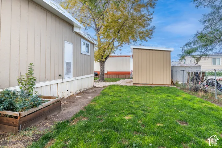 Manicured lawn with a detached storage shed, a wood-framed planter box, and a gravel path