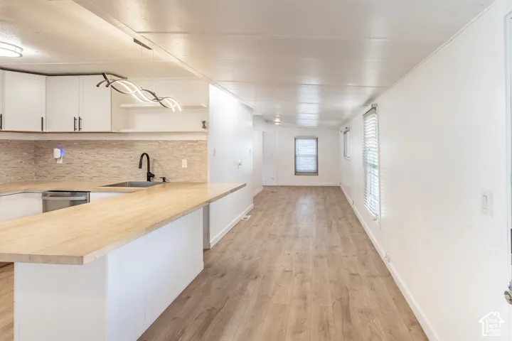 Open-concept living space featuring wood-finish flooring, white walls, and multiple windows