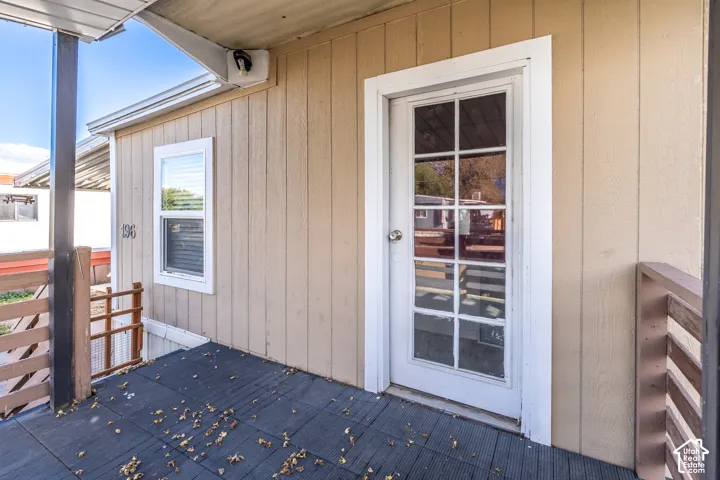 Entry door with glass paneling, durable exterior siding, and a window with blinds