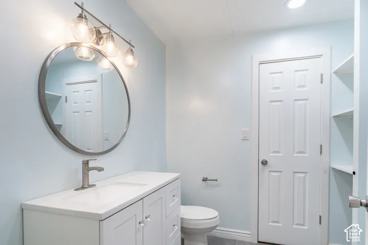 White vanity with a solid surface countertop, brushed nickel faucet, and a circular framed mirror