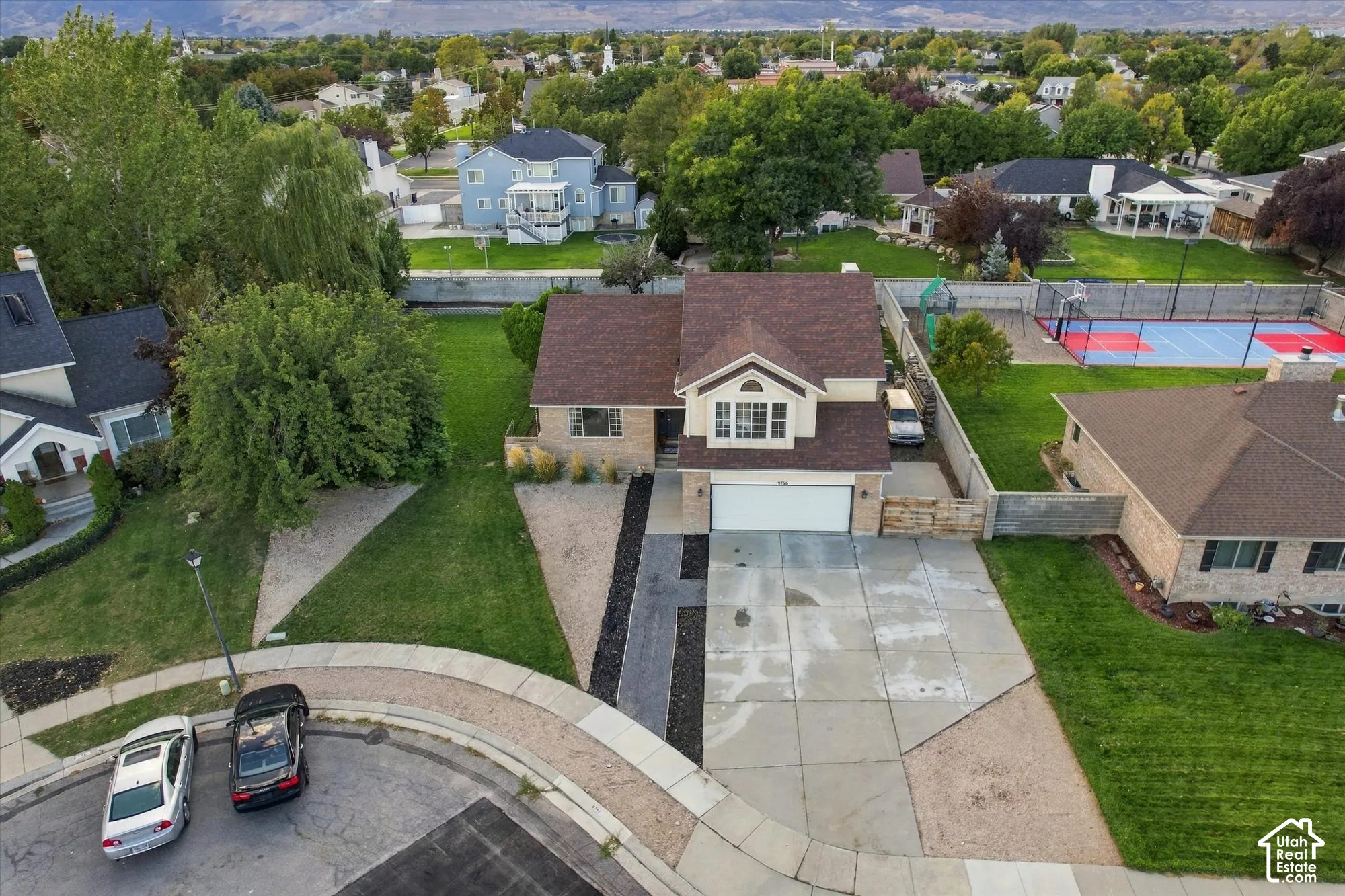 Two-story residence with an attached garage, paved driveway, and mature landscaping