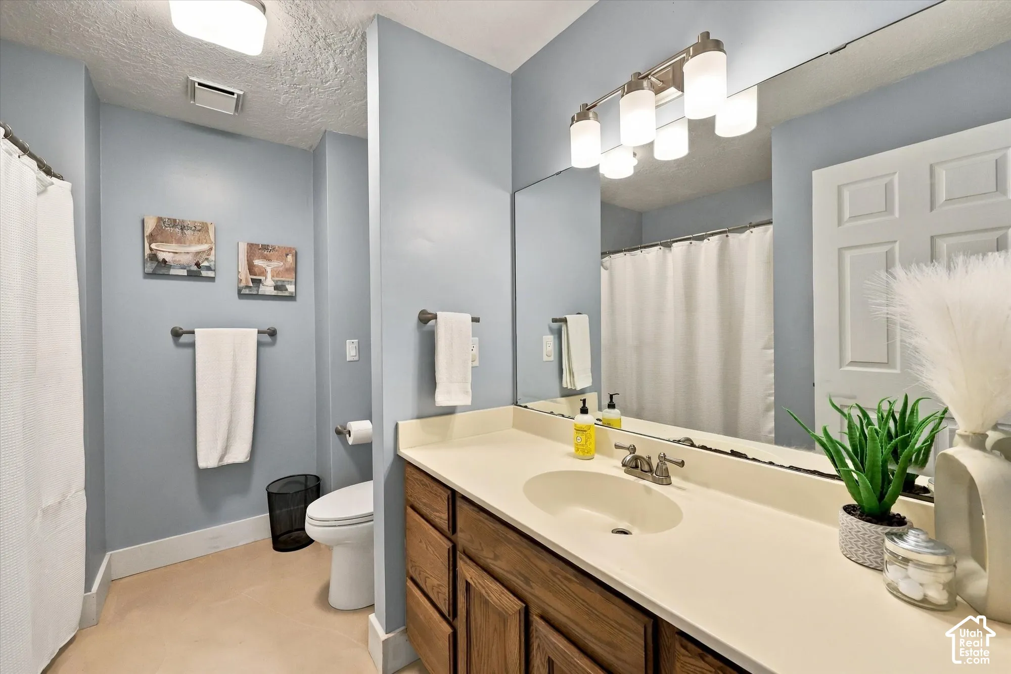 Vanity with wood-finish cabinetry, integrated sink, and light-toned countertop