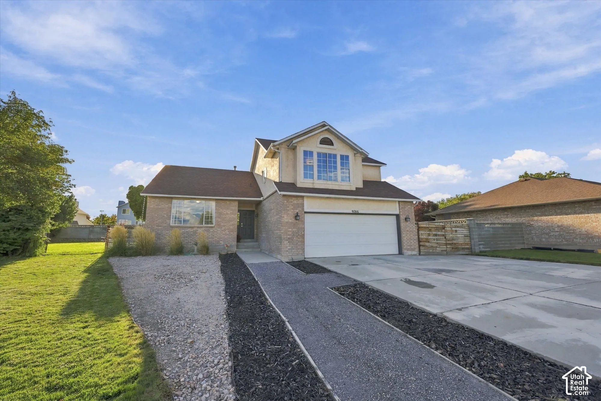 Two-story residence featuring a brick and stucco exterior, an attached two-car garage, and a concrete driveway