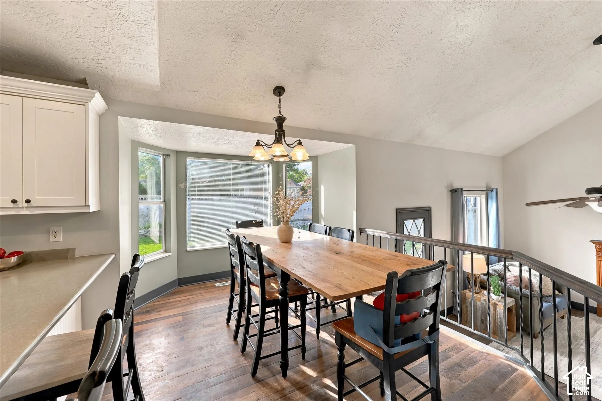 Hardwood flooring with a multi-light chandelier, featuring a bay window