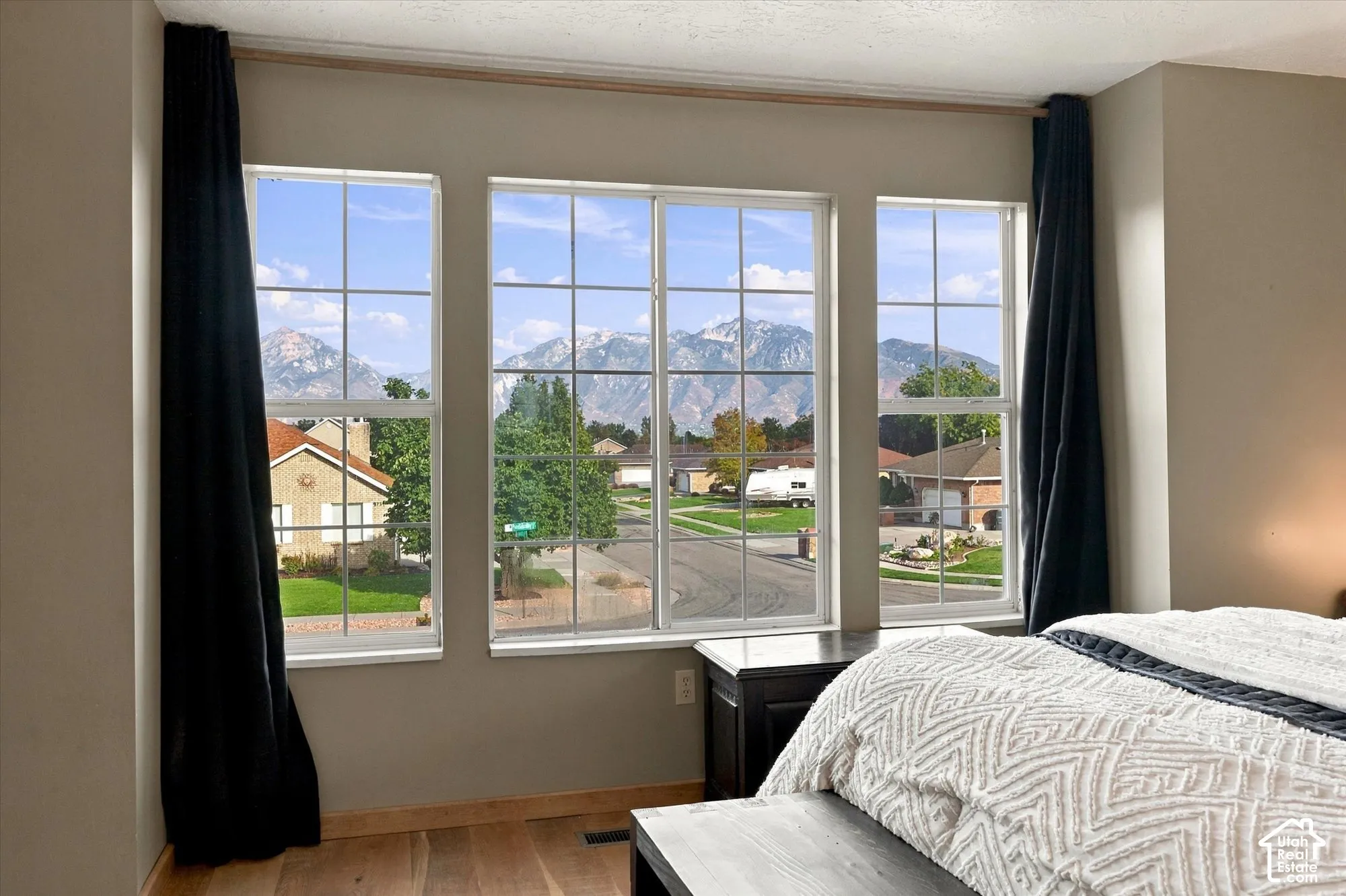 Triple picture windows with grids, light wood-finish flooring.