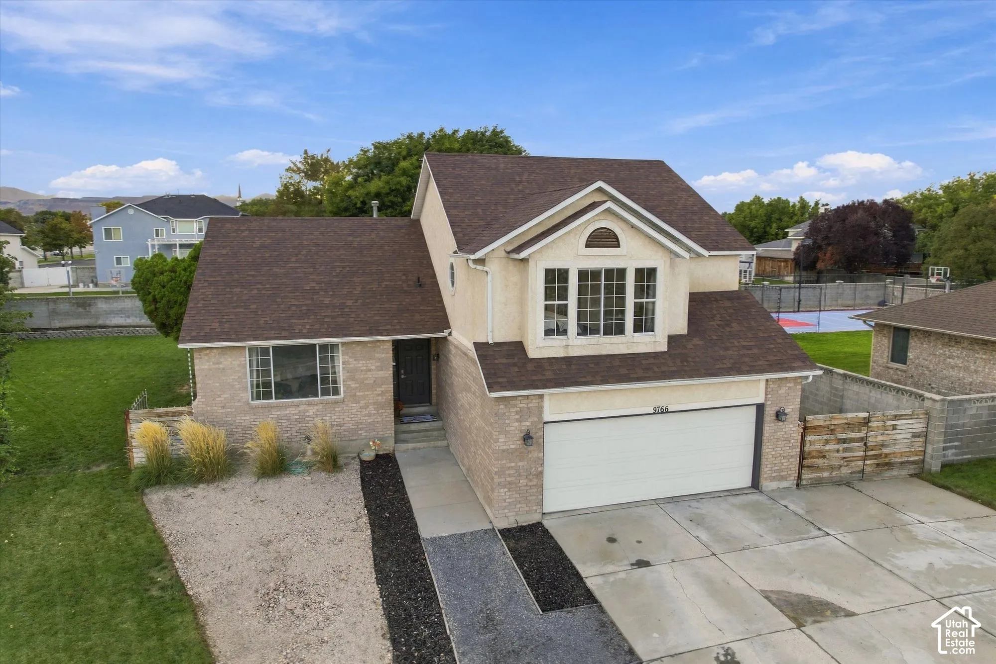 Two-story residence featuring light brick and stucco siding, an attached two-car garage, and a concrete driveway