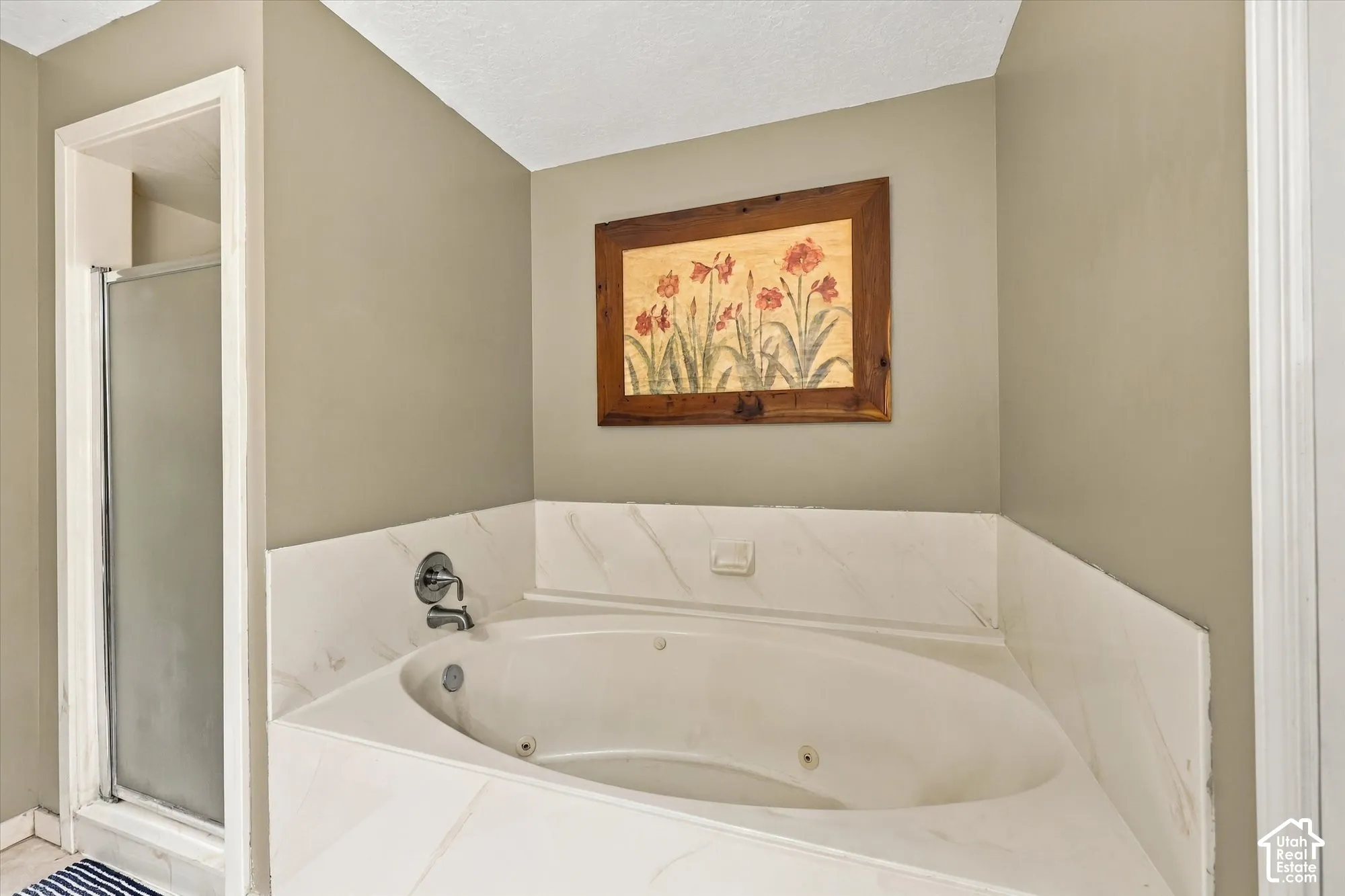 Jetted soaking tub with a tiled surround, complemented by a glass-enclosed shower