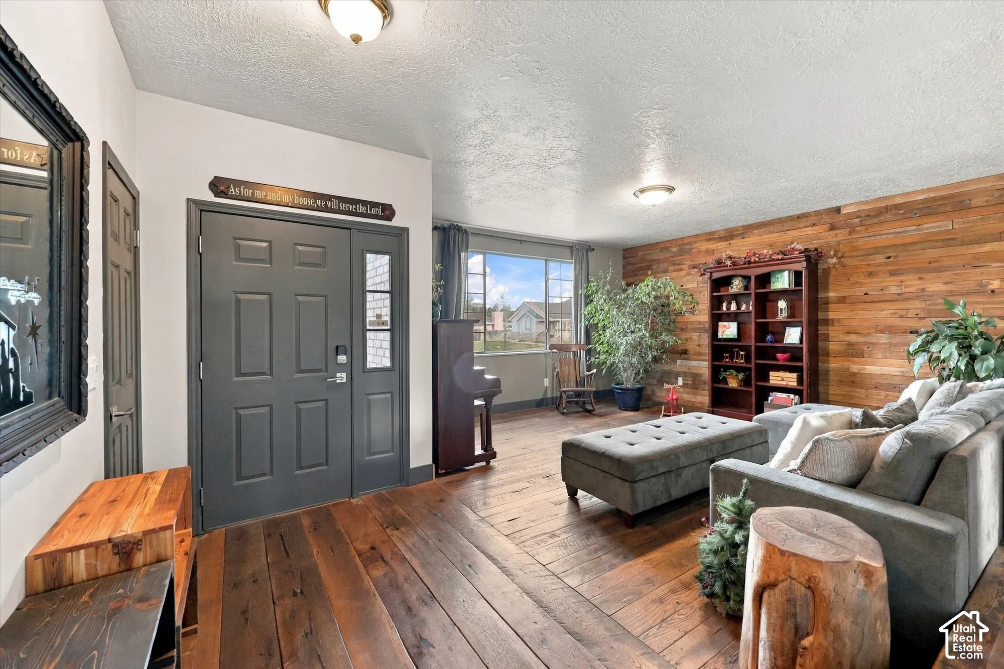 Hardwood flooring throughout, accent wall with horizontal wood paneling, entry door with sidelight.