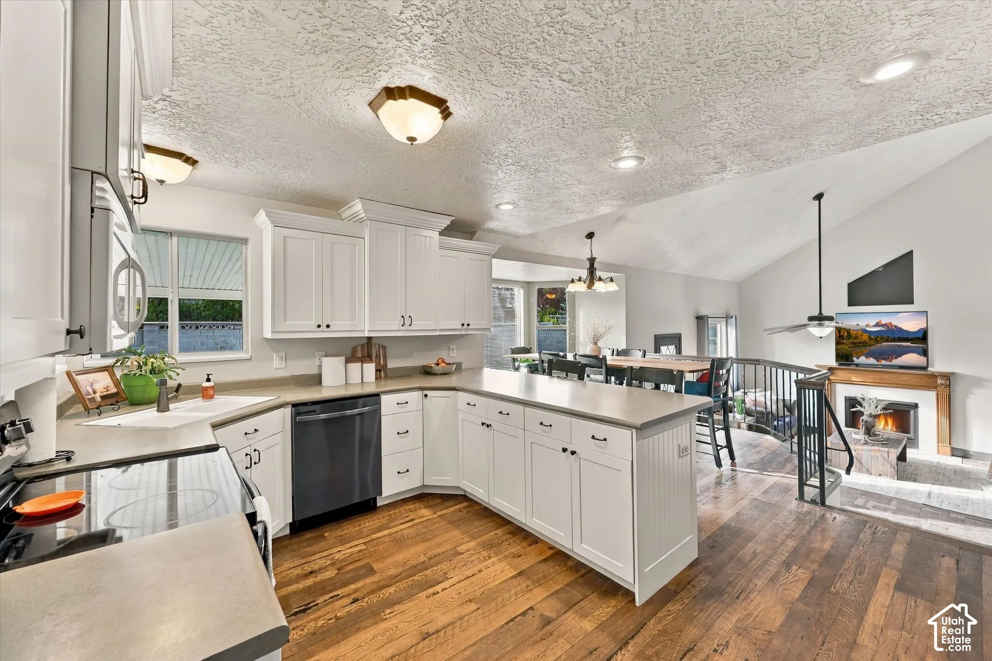 Kitchen featuring white cabinetry, hardwood flooring, and a built-in dishwasher