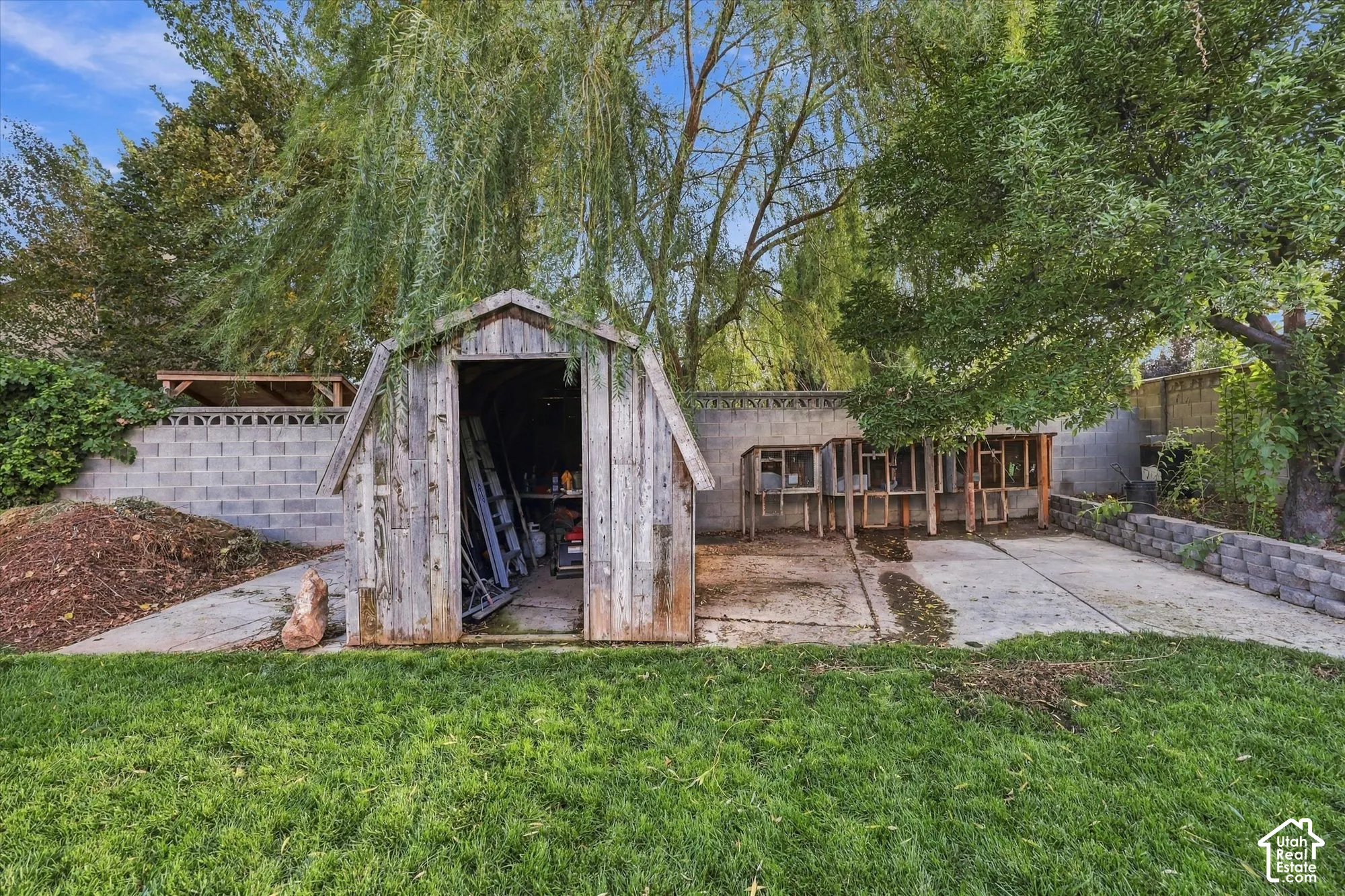 Expansive grass lawn with a storage shed and a concrete block retaining wall