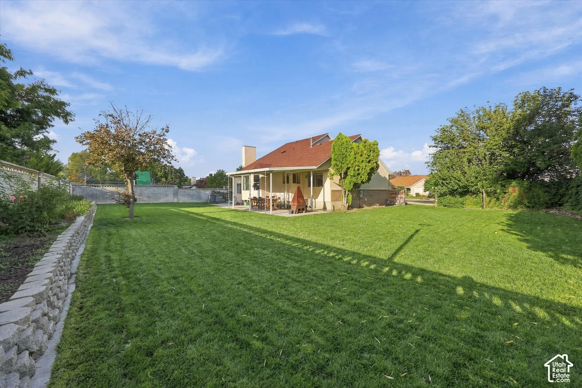Expansive lawn area with mature trees and a stone retaining wall