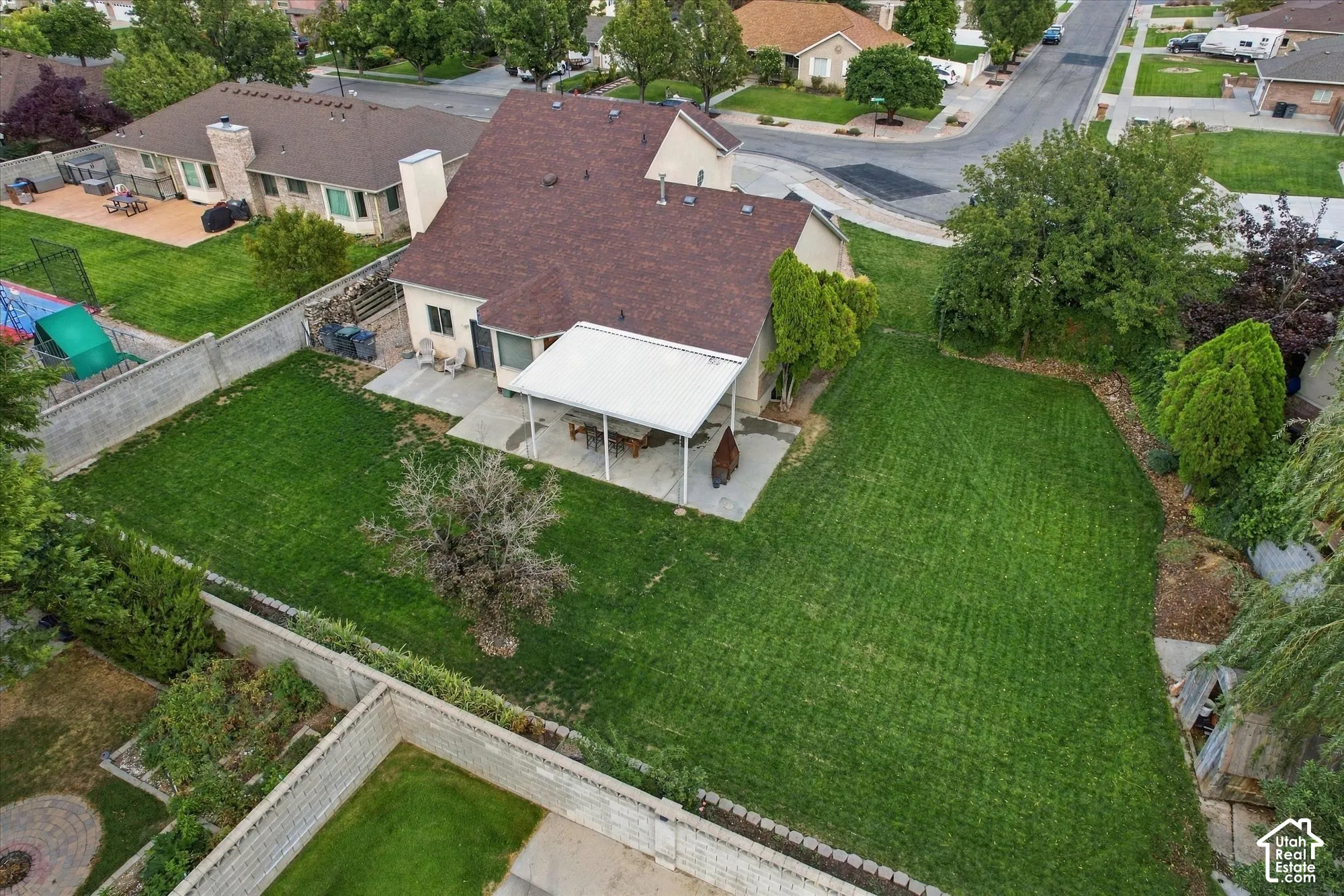 Expansive lawn area with a covered patio and concrete hardscaping