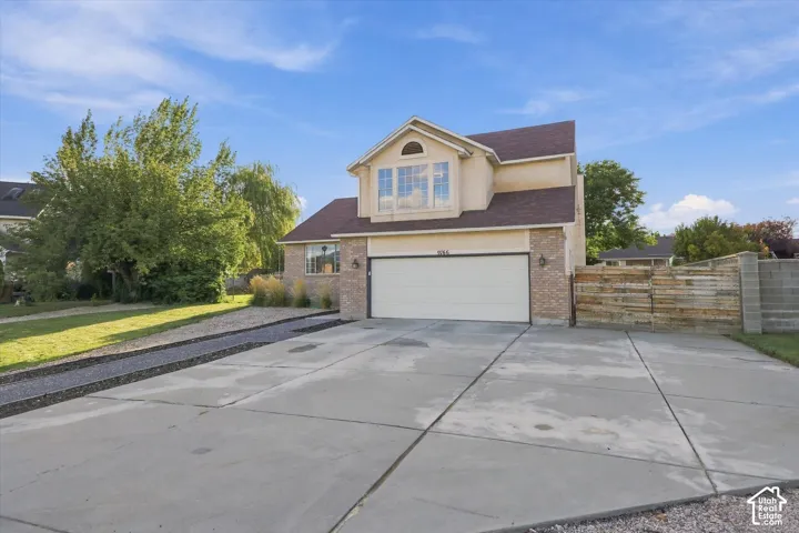 Two-story stucco and brick exterior, attached two-car garage, concrete driveway, and a partially fenced yard