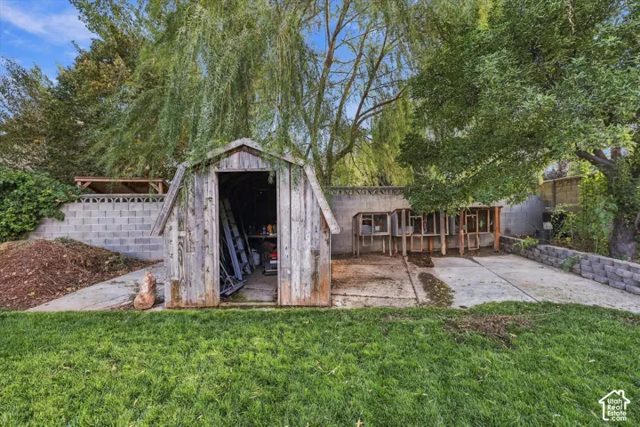 Expansive grass lawn with a storage shed and a concrete block retaining wall