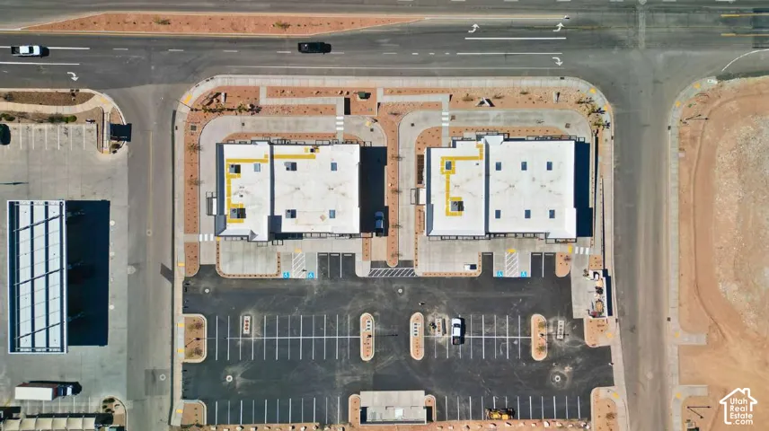 Two commercial buildings with flat roofs, expansive paved parking areas, and adjacent roadways