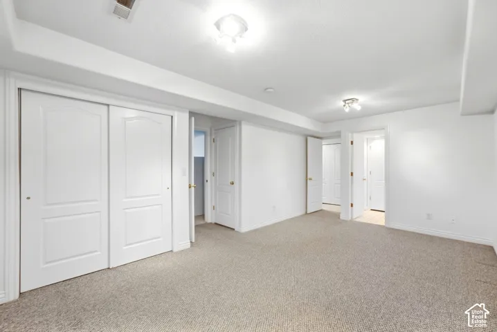 Carpeted flooring, white walls, multiple doorways, and recessed lighting