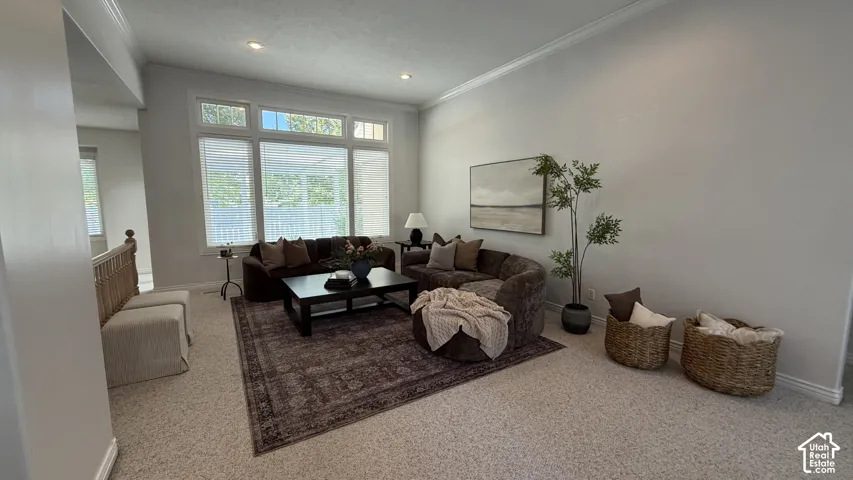 Bright living area featuring high ceilings, crown molding, recessed lighting, and large windows
