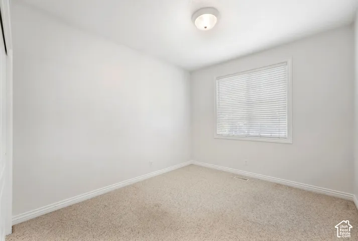 Carpeted flooring, white walls, white window blinds, and an overhead flush-mount light fixture