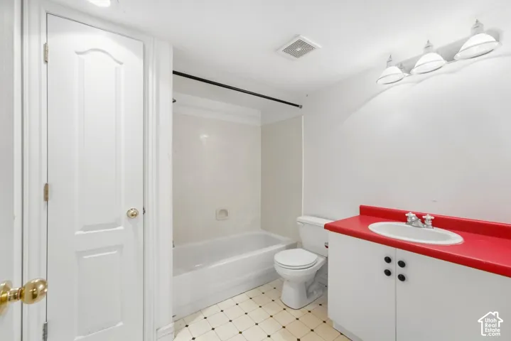 White wall paint, vanity with red countertop, white cabinet, tub with shower, and tiled flooring