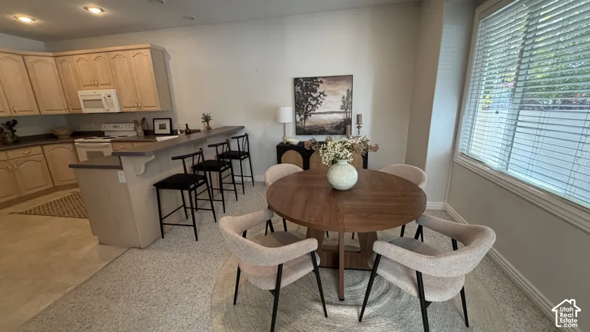 Kitchen featuring light wood cabinetry, white appliances, a breakfast bar, and recessed lighting