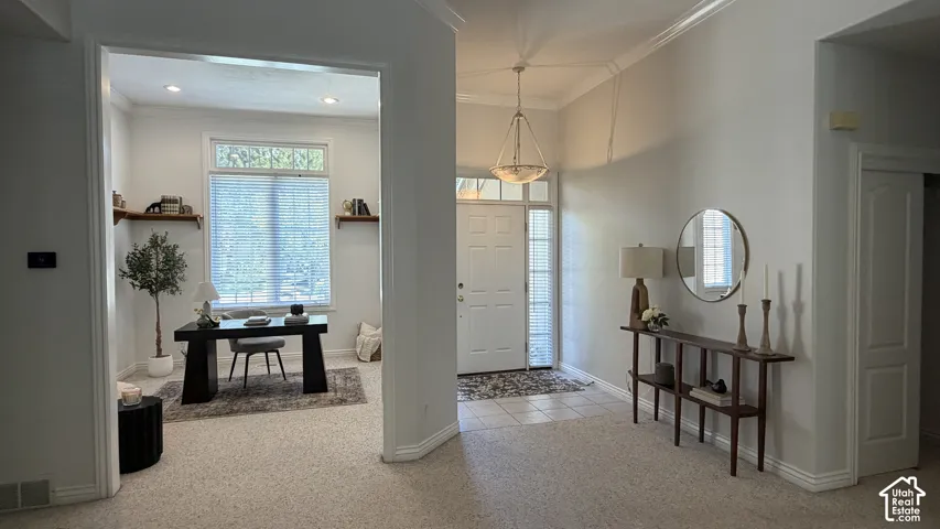Recessed lighting, crown molding, white wall finishes, built-in shelving, and a prominent front door with sidelights